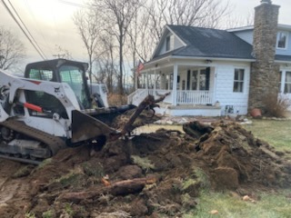 Skid steer excavating and hauling debris from a residential front yard