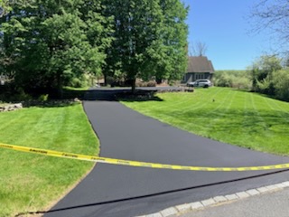 Freshly sealcoated curved driveway winding up to home with lush green lawn