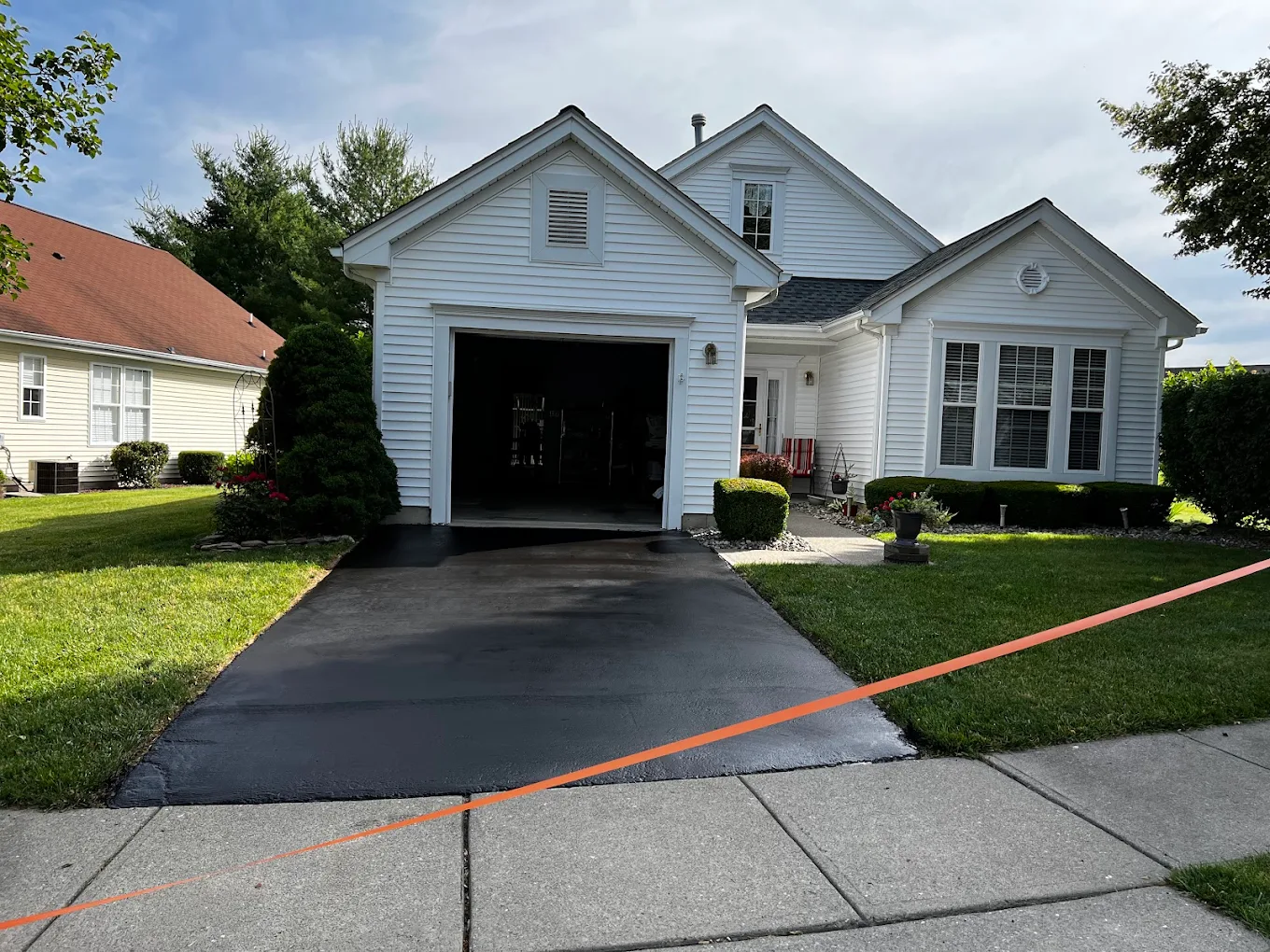 Sealcoated driveway on white colonial home with crisp edges
