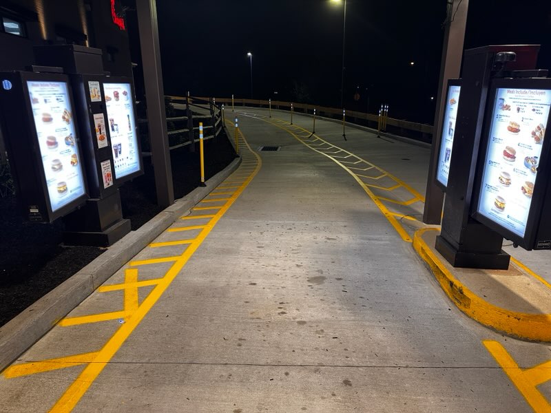 Fresh yellow curb striping along a drive-thru lane at night