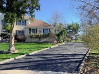 Faded gray asphalt driveway before sealcoating