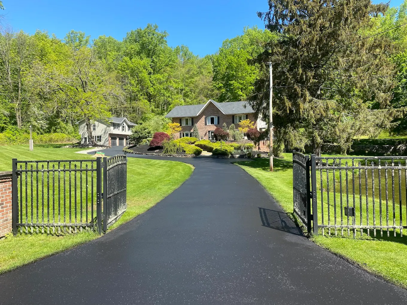 Sealcoated driveway through iron gate entrance to brick home