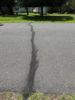 Close-up of large asphalt crack running across driveway before crack filling