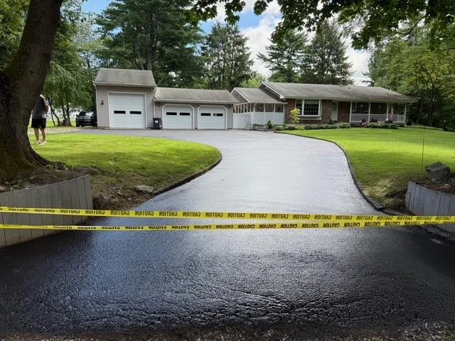 Freshly sealcoated ranch-home driveway with caution tape, NJ